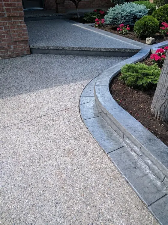 Exposed aggregate walkway with a grey border around a garden bed