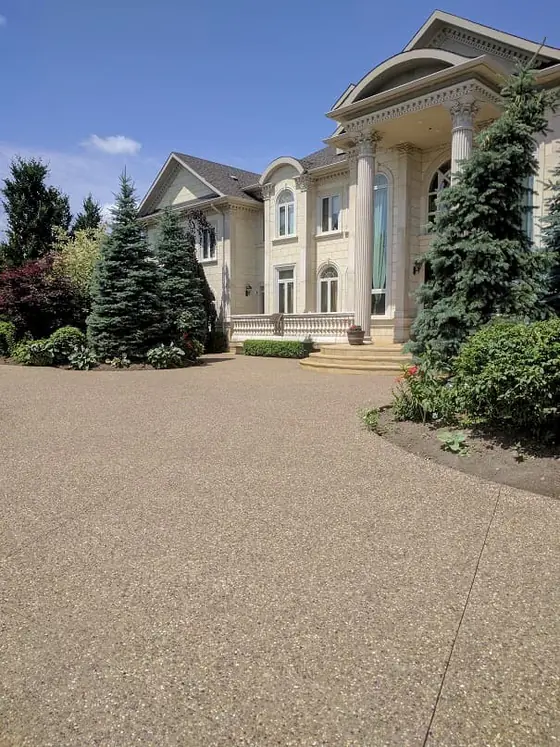 Exposed aggregate driveway leading to a landscaped home