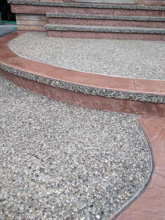 Exposed aggregate entrance framed by a warm red decorative border