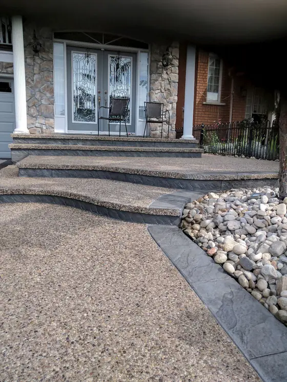 Exposed aggregate steps and walkway beside a stone landscape bed