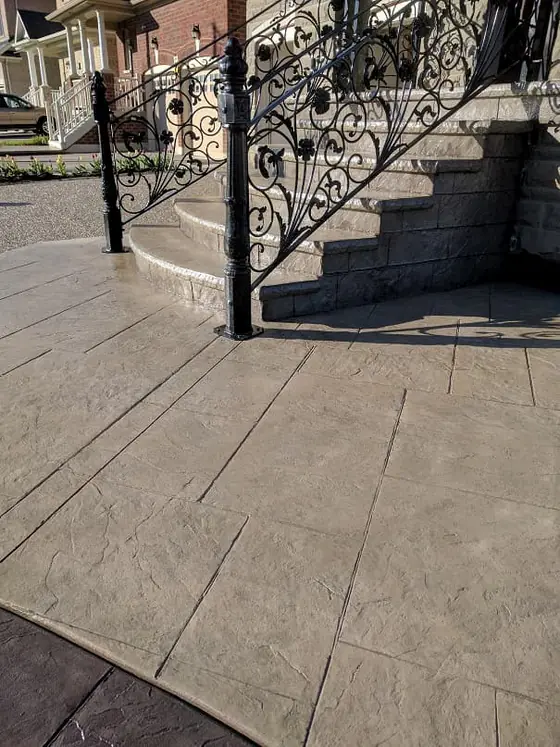 Stamped concrete entrance framed by black iron railings