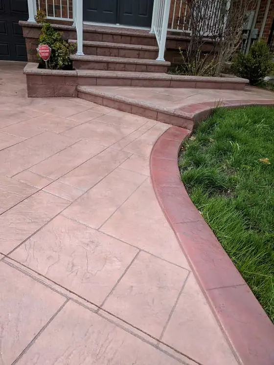 Reddish stamped concrete walkway with a curved lawn border
