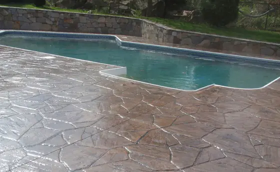 Sealed stamped concrete pool deck beside clear blue water