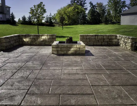 Stamped concrete patio with a central fire pit and stone seating walls