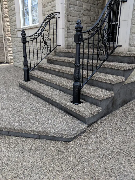 Exposed aggregate front steps with black decorative railings