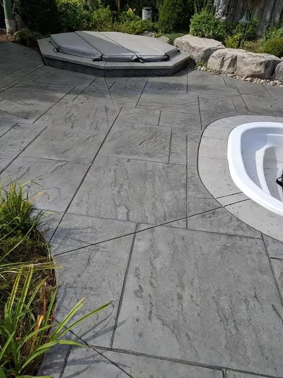 Textured stamped concrete patio alongside a rounded pool edge
